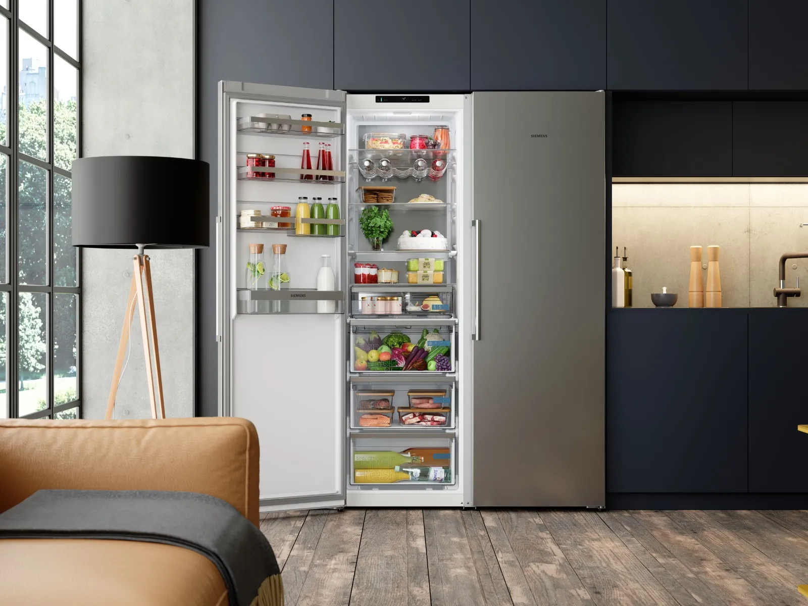 Un réfrigérateur en acier inoxydable ouvert, rempli de produits frais, dans une cuisine moderne aux placards foncés et au sol en bois.