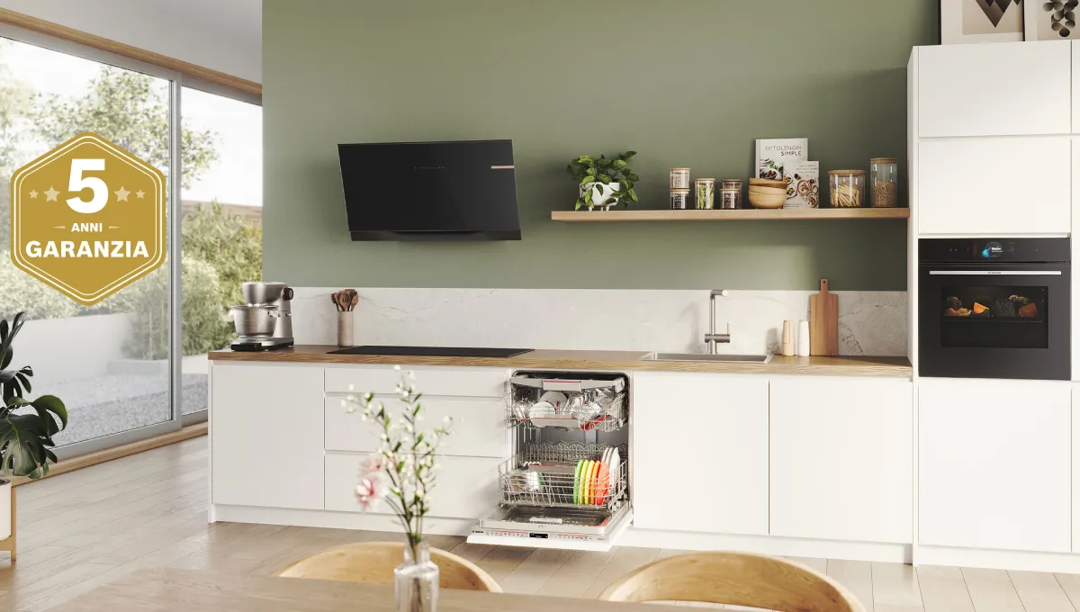 Cucina moderna con mobili bianchi, lavastoviglie aperta, forno incassato e finestra ampia con vista esterna