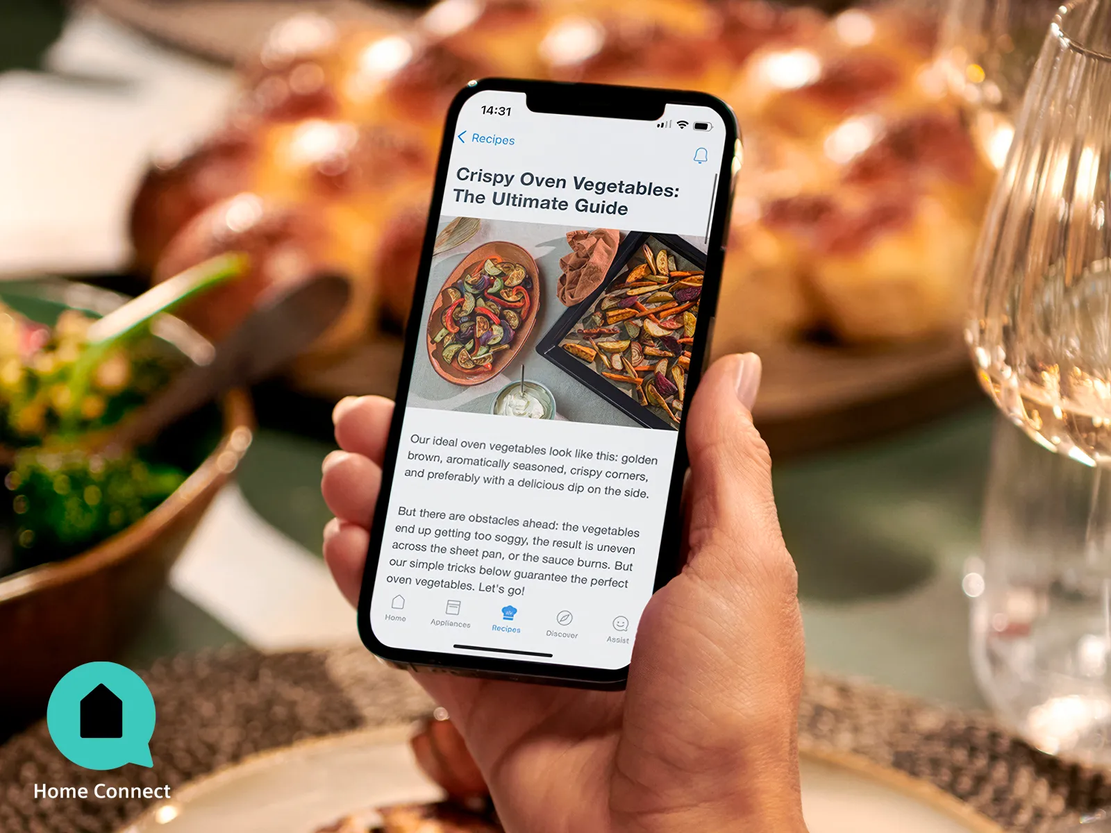 Persona che tiene in mano uno smartphone che mostra un'app per la consegna di cibo su una tavola imbandita con cibo e calici di vino.