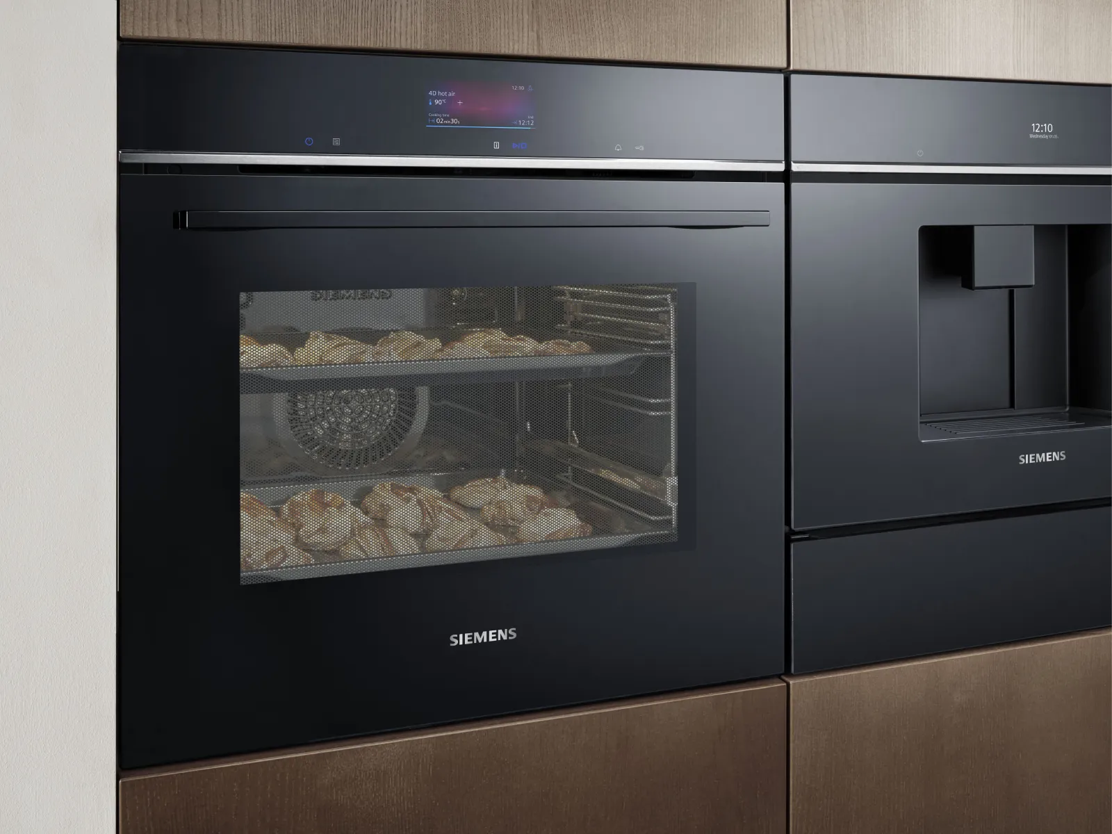 Siemens oven with three levels of food: fish with asparagus, and fruit & cream desserts. Digital display shows settings.