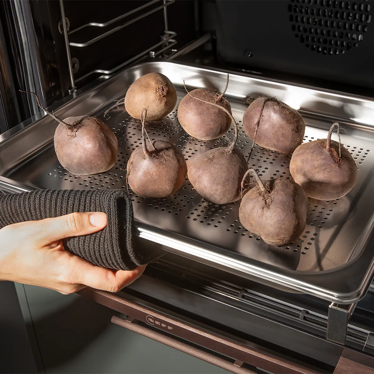 Baked potatoes in oven, hand reaching to remove tray, kitchen appliance interior.
