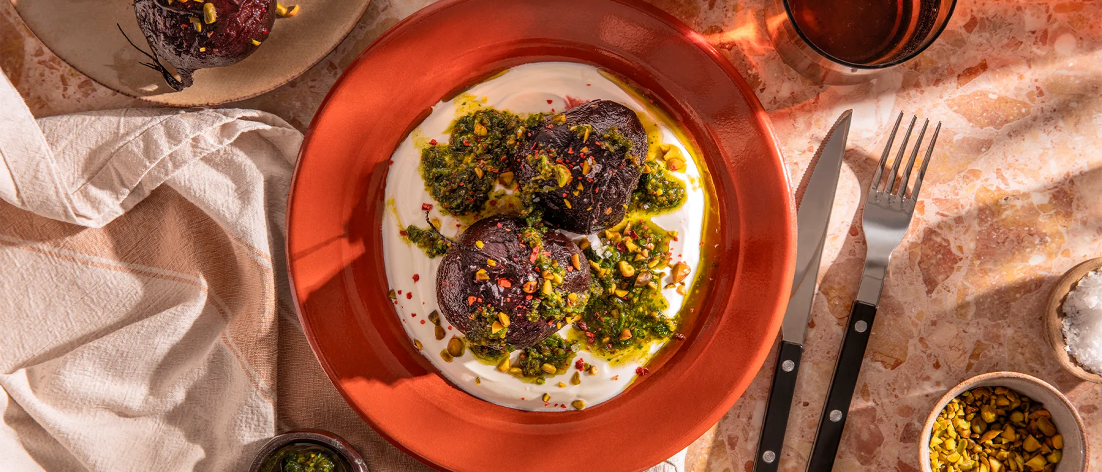 Vibrant roasted beets with creamy yogurt, fresh pesto, and crunchy pistachios, beautifully plated. A delicious and healthy meal.