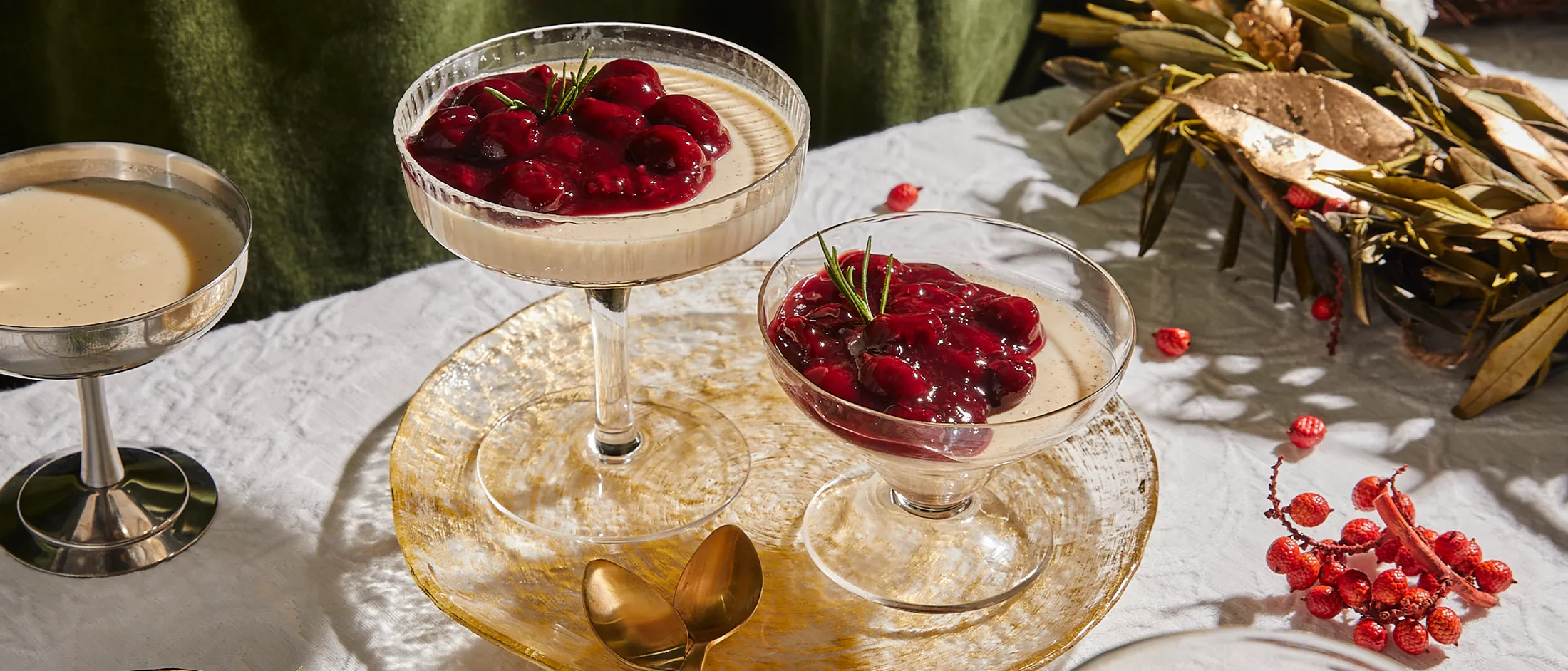Dessert dishes with red cherries, gold spoons, and a festive holiday setting.