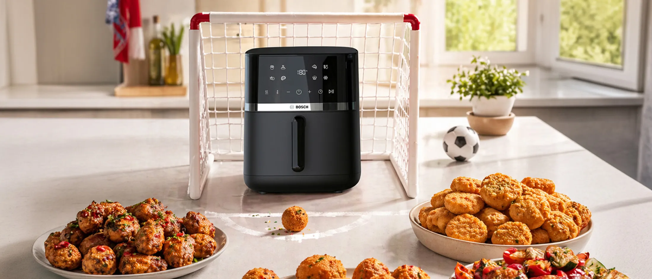 Air fryer na stolu ispred gola i grickalice ispred njega.