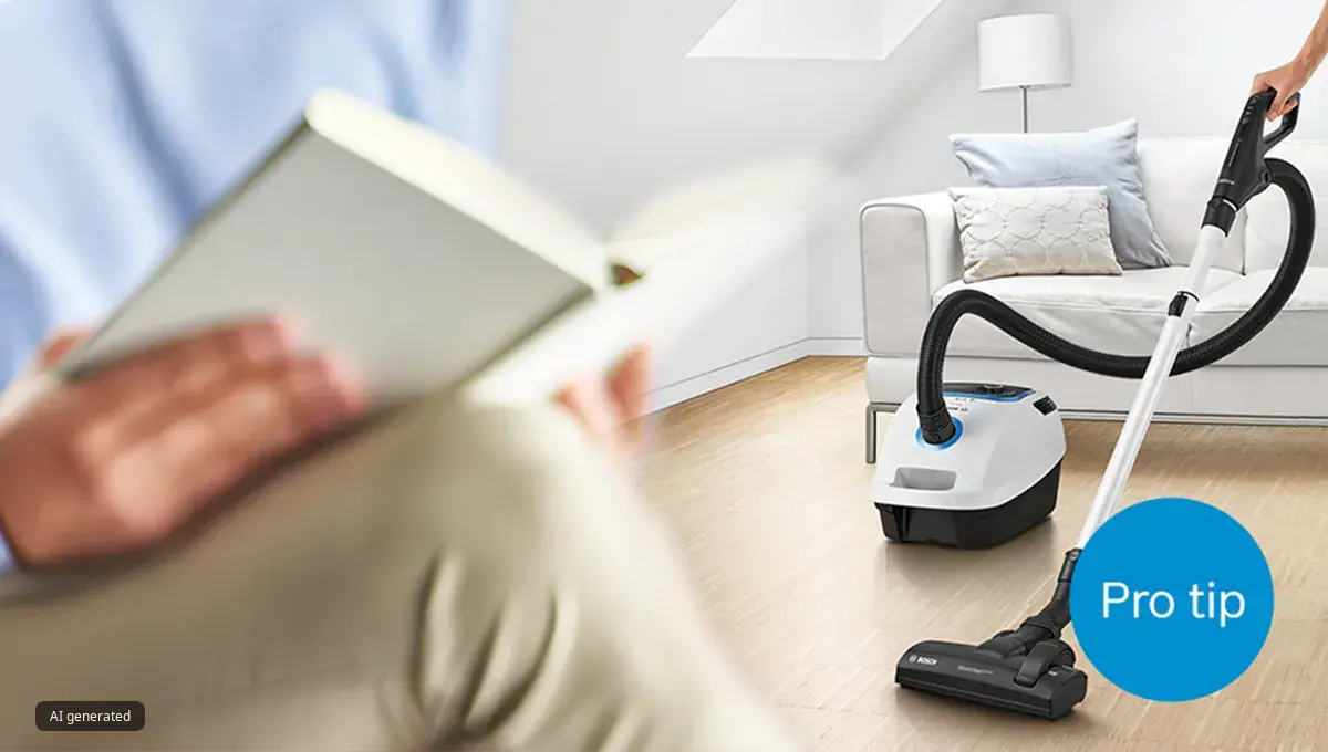 Person cleaning living room with bagged Bosch ProSilence vacuum while someone else reads