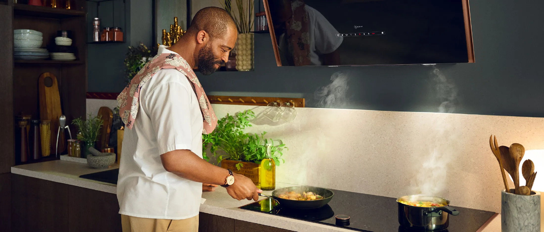 Man cooking in kitchen, preparing food on stove, hob in background.