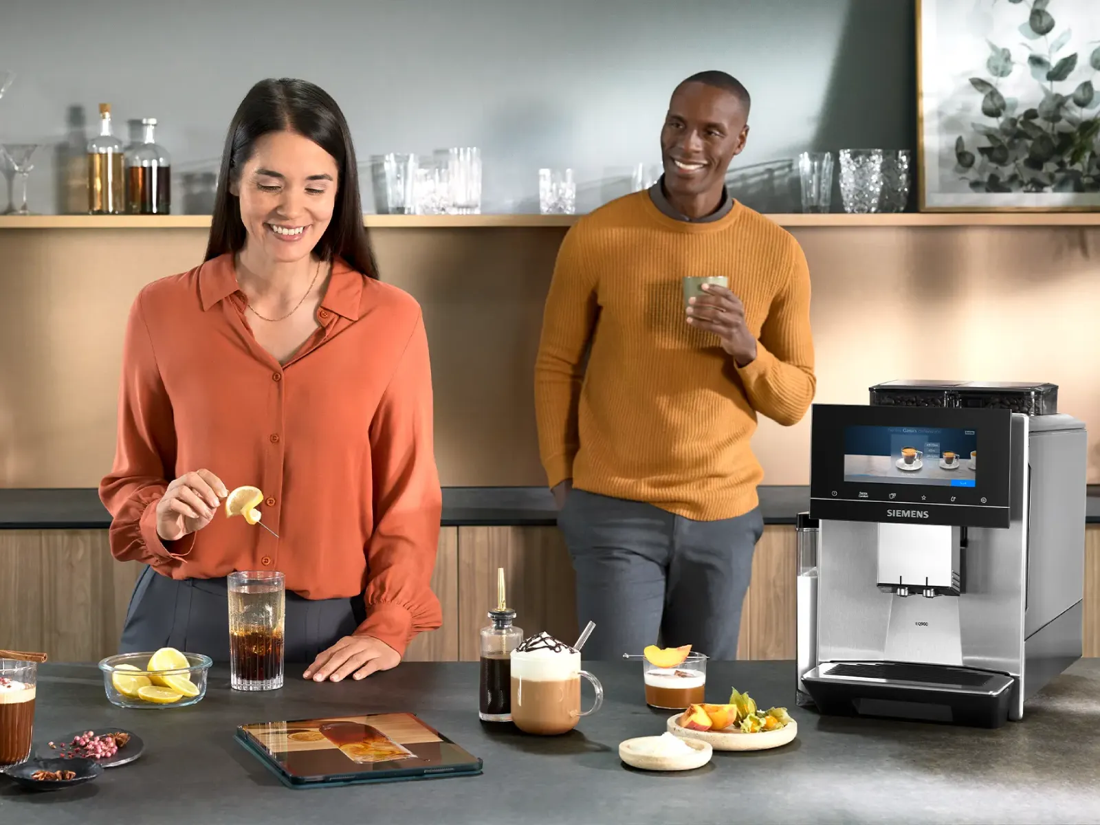 Ett par i ett modernt kök som gör kaffebaserade cocktails och andra kaffedrycker med en Siemens kaffemaskin.