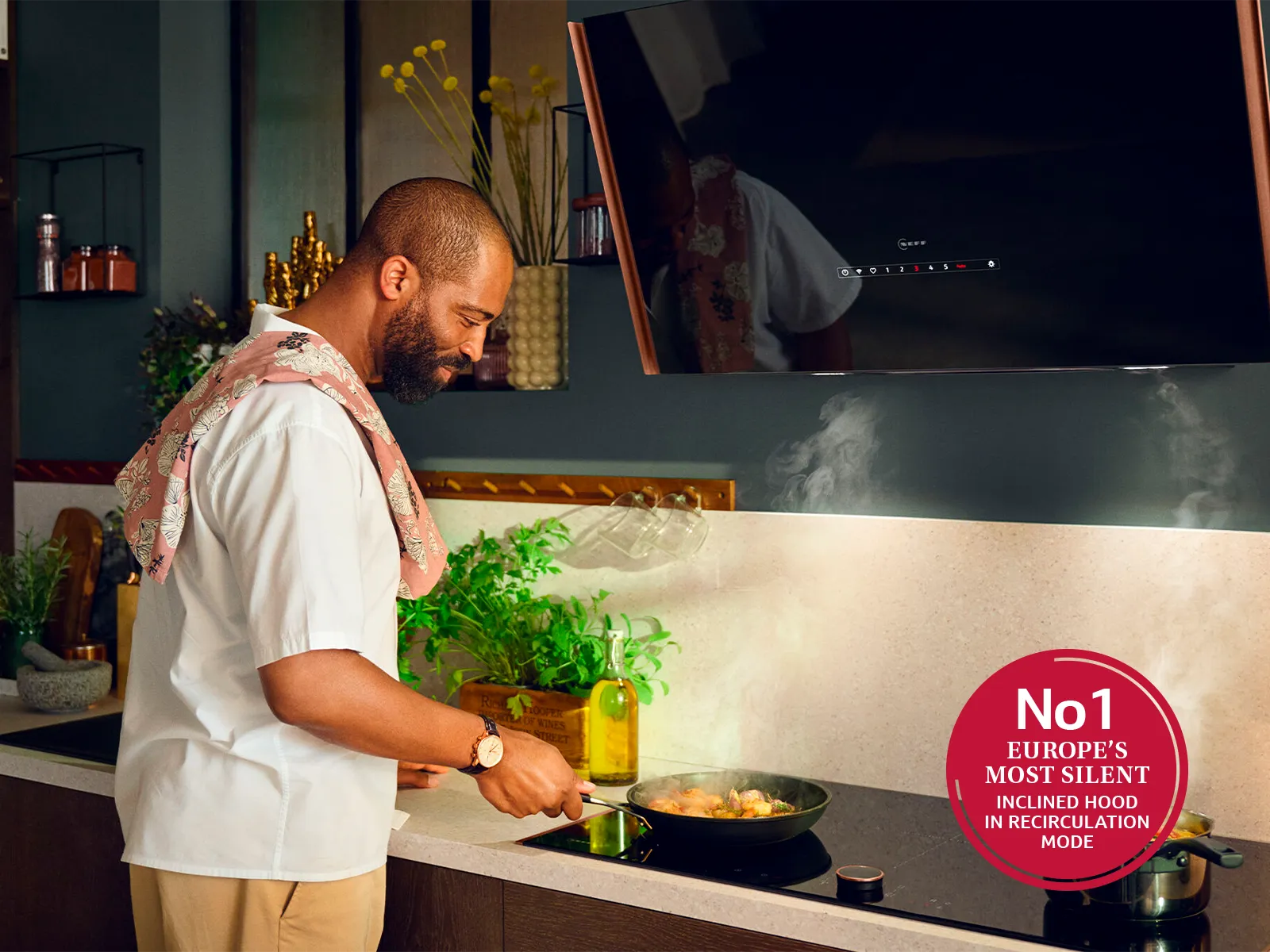 A man is preparing food in a kitchen using the NEFF inclined hood.