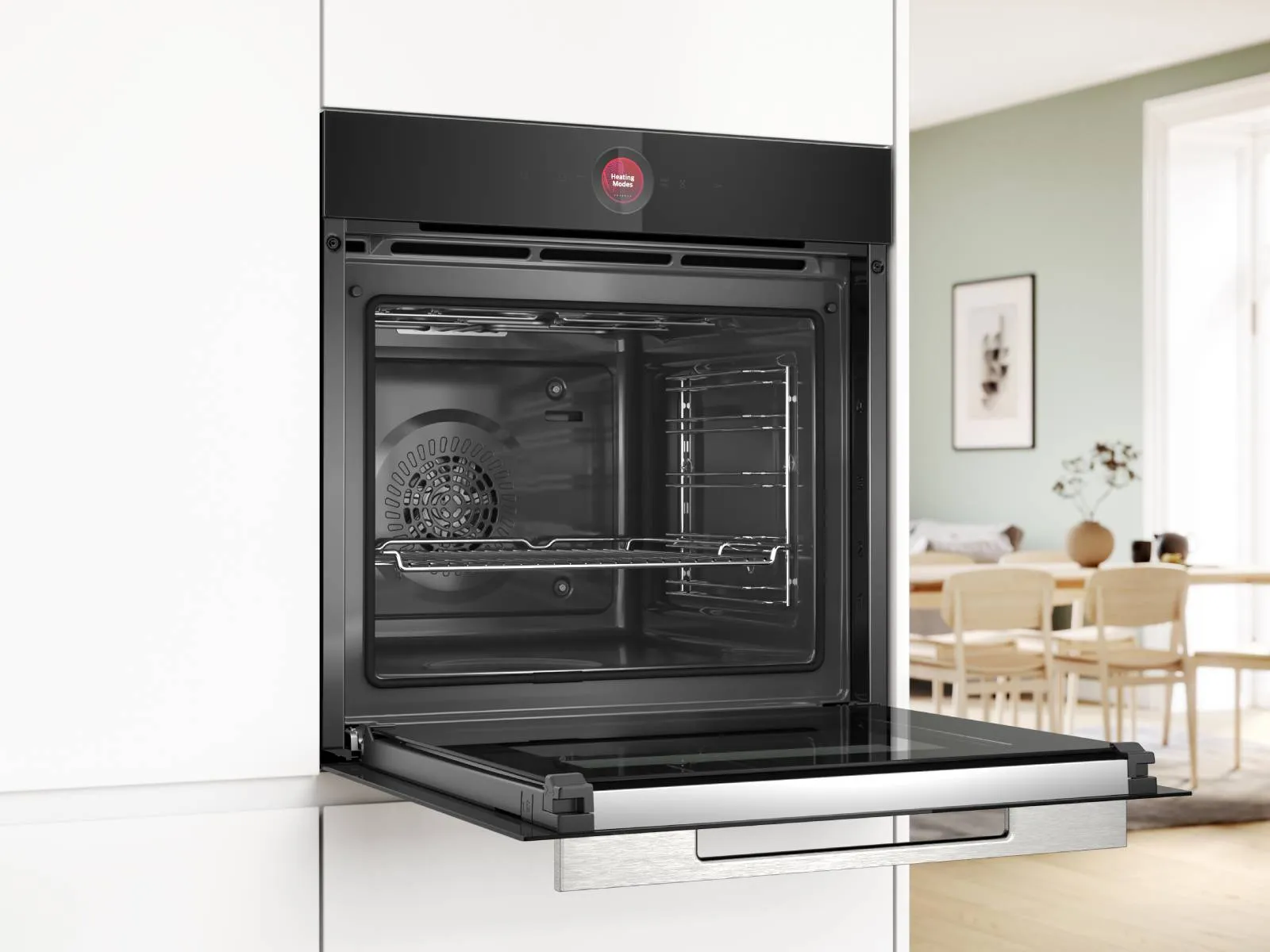 A modern kitchen with integrated black Bosch appliances, including a stacked oven and microwave, an open dishwasher, and a black extractor hood, all set against white walls and light wooden countertops.