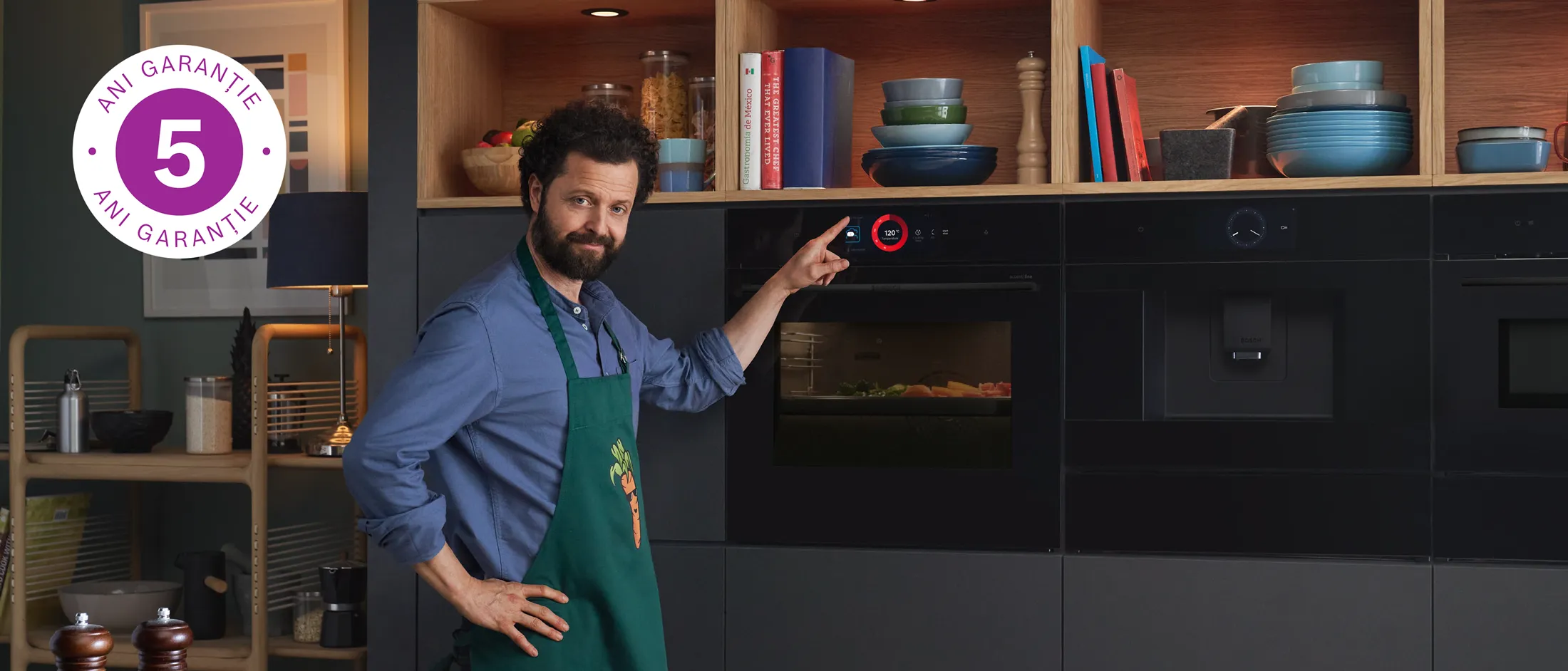 O persoană arată spre un cuptor încorporat Bosch, într-o bucătărie cu nuanțe de lemn echipată și cu alte electrocasnice încorporabile