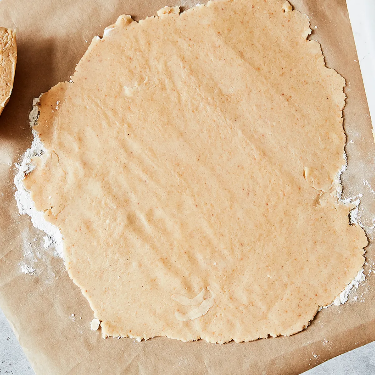Rolled-out dough on parchment paper, dusted with flour, ready for baking.