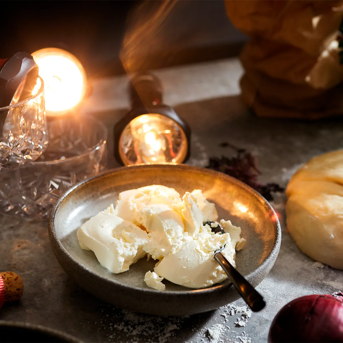 Rustic table setting with wine, bread, cheese, and other food items in warm lighting.