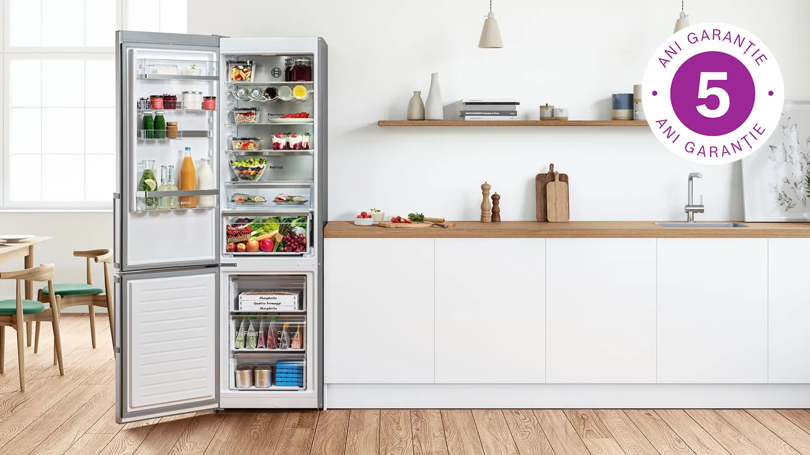 Combină frigorifică independentă cu ușa deschisă cu diverse alimente vizibile, în dreapta sus logo 5 ani garanție