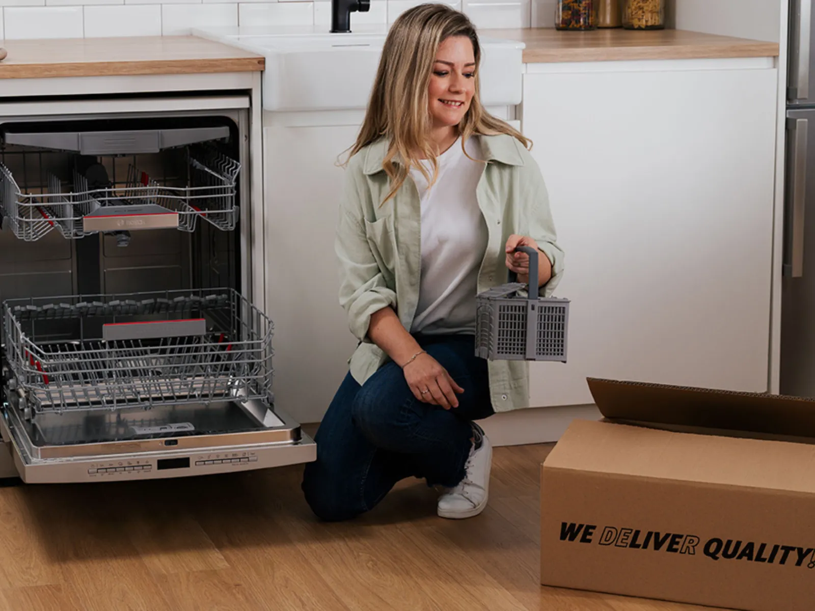 Bosch customer standing next to a dishwasher with a cutlery basket accessory and a delivery box