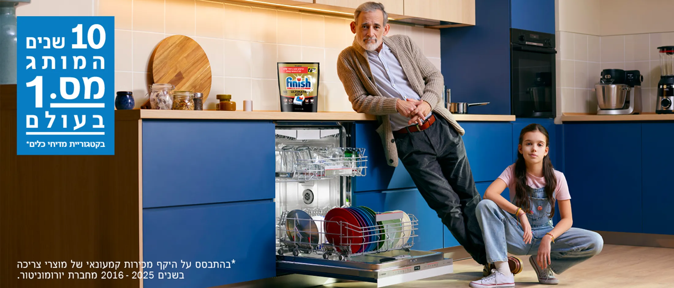 Man leaning on kitchen counter next to open dishwasher and seated girl on floor in modern kitchen with blue cabinets