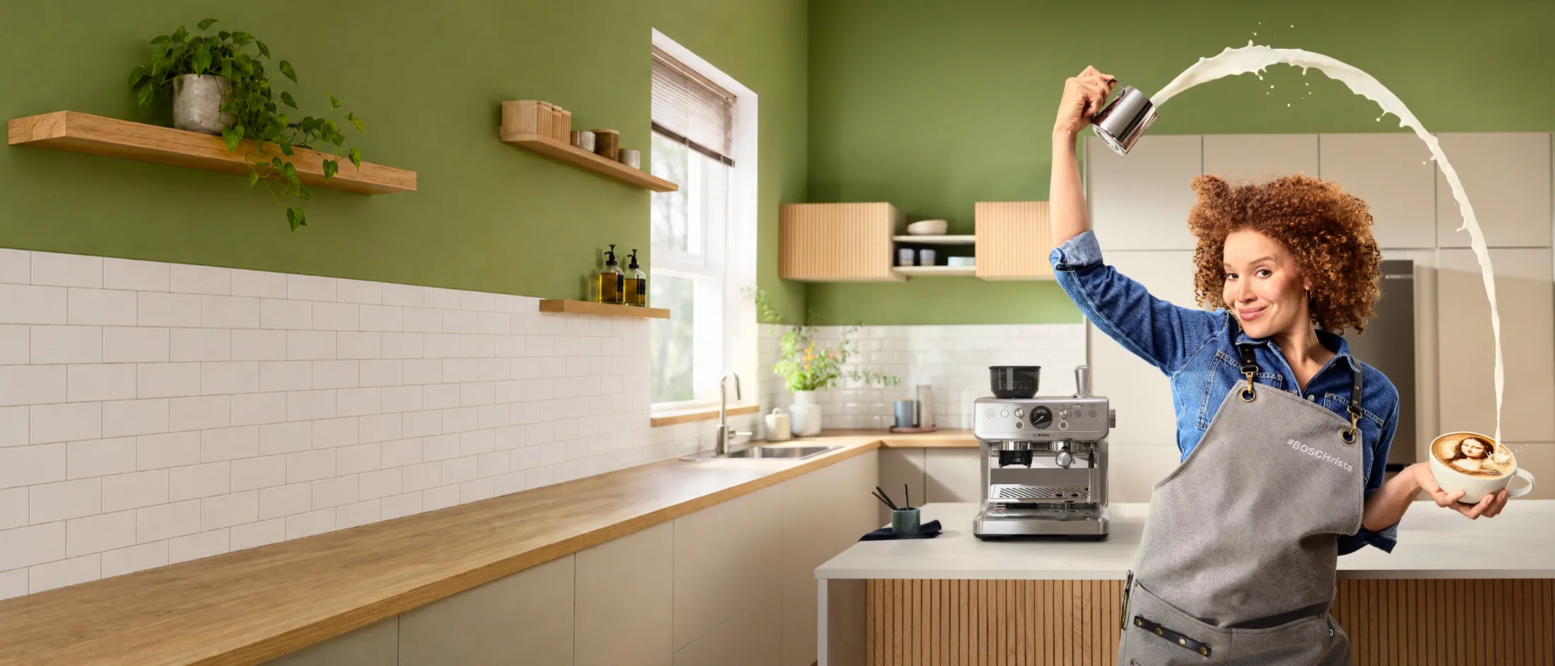 Une barista, vêtue d'un tablier #BOSCHrista, s'amuse à dessiner la Joconde en versant du lait dans une tasse pour créer un latte art, avec une machine à expresso Bosch en arrière-plan.