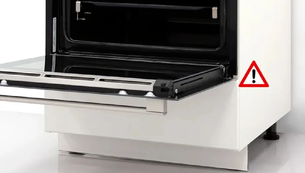 Oven med öppen dörr, varningsskylt på displayen, köksapparat på vit yta.