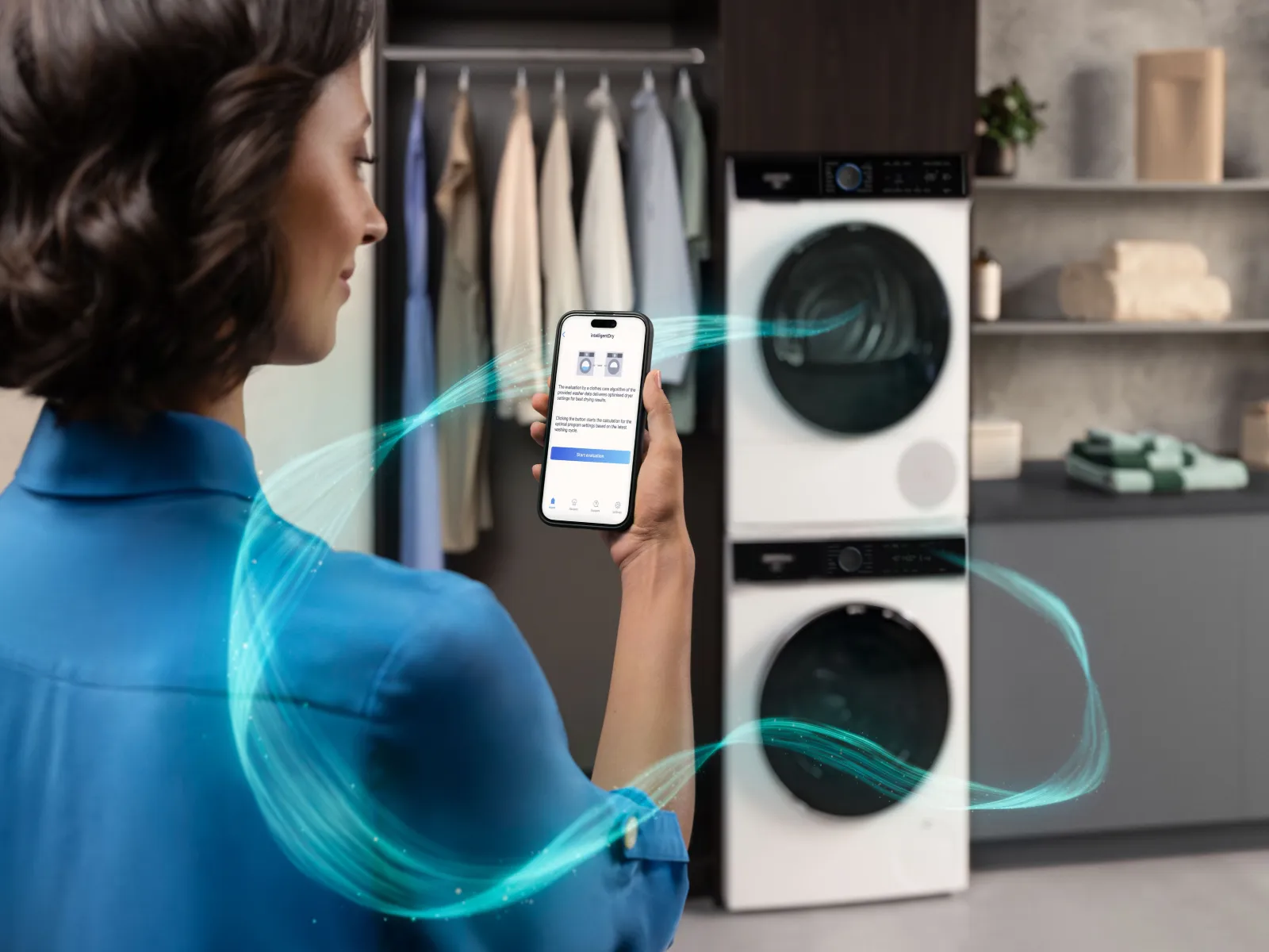 Woman uses "intelligentDry" app on her phone to optimize smart washer and dryer settings, with glowing blue lines showing connectivity.
