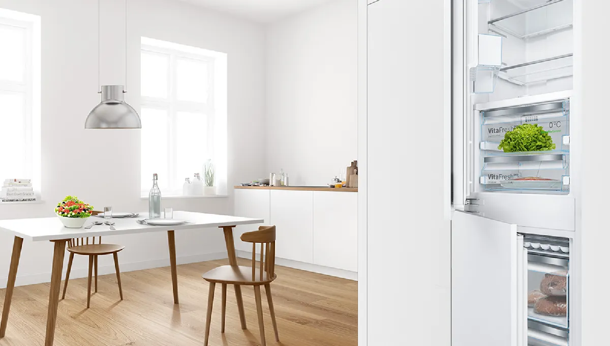 Lyst, moderne kjøkken med hvite vegger, et trebord og åpne kjøleskap som viser frem ferske råvarer.