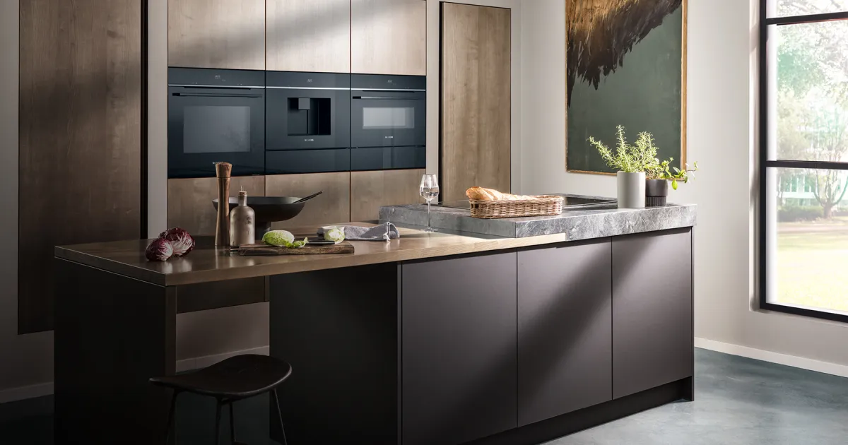 Modern kitchen featuring sleek built-in black appliances, a stone countertop, and decorative elements like a painting and a bread basket.