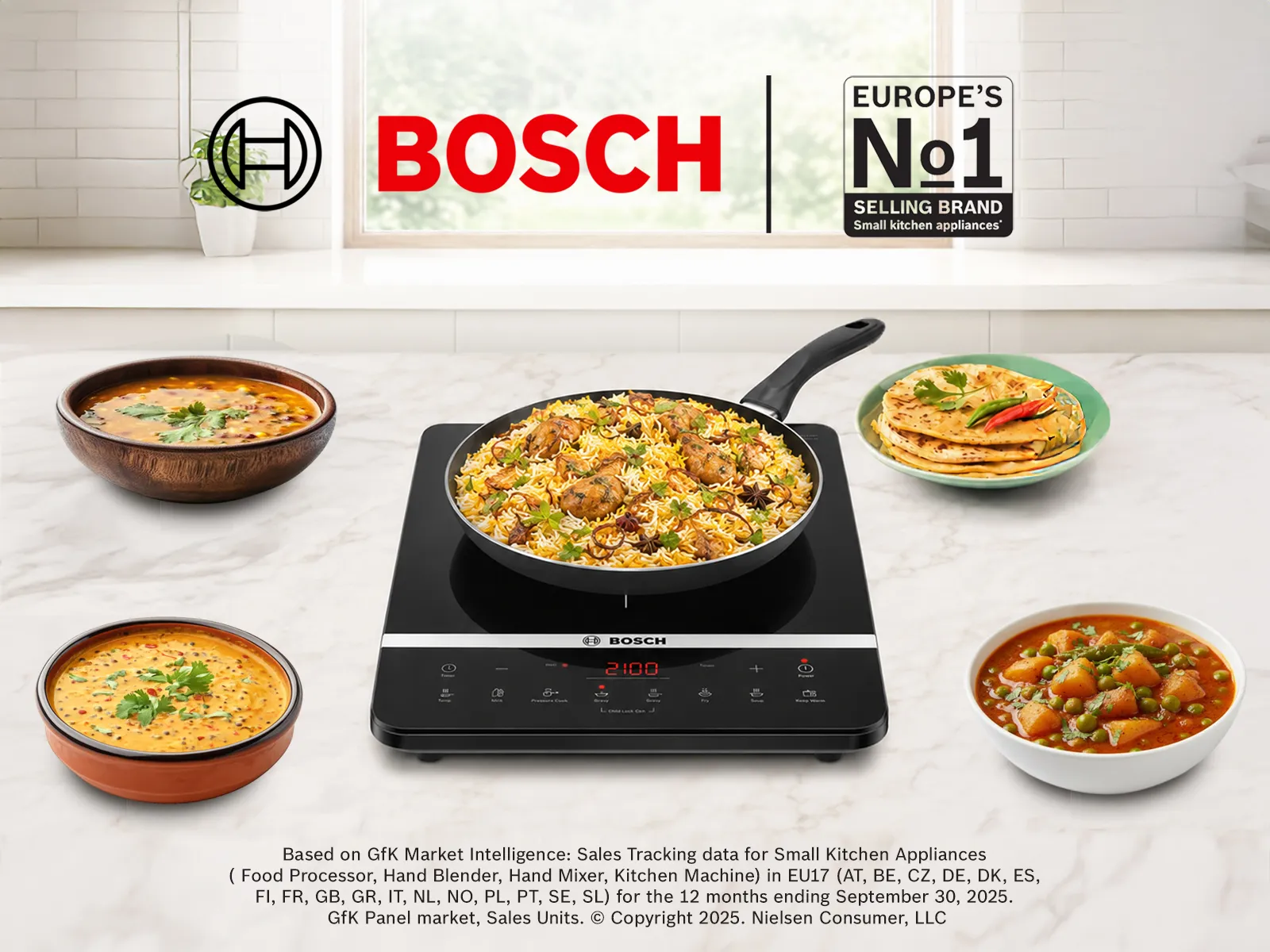 A Bosch portable induction cooktop on a kitchen counter surrounded by bowls of Indian food.