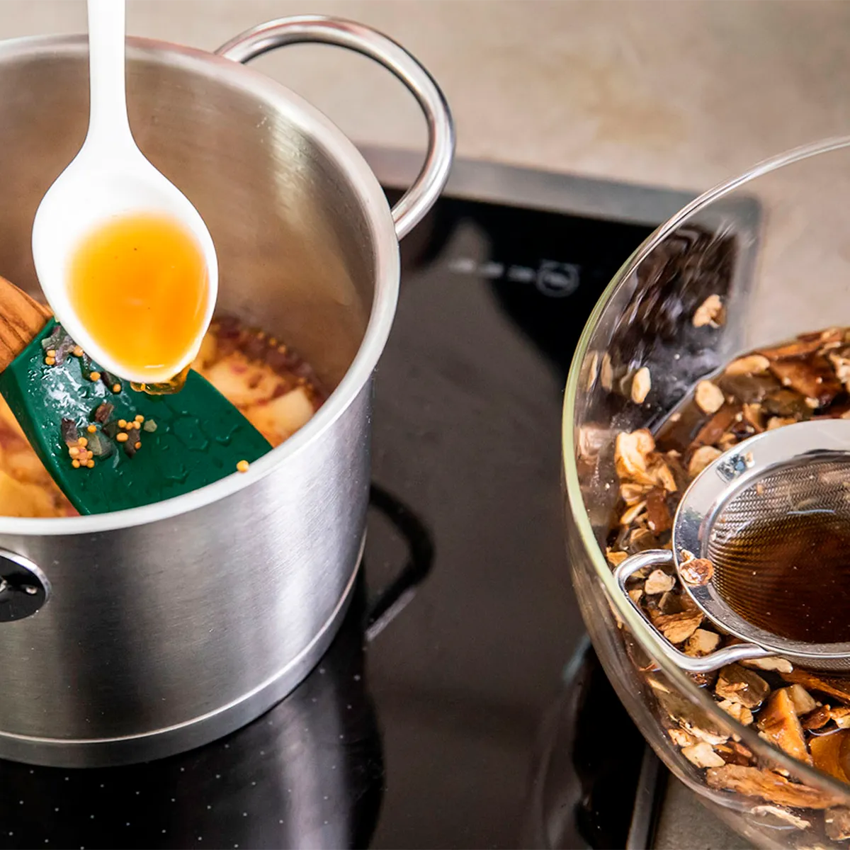 Stainless steel pot on a stove with seasoning, beside a glass bowl with filtered spices.