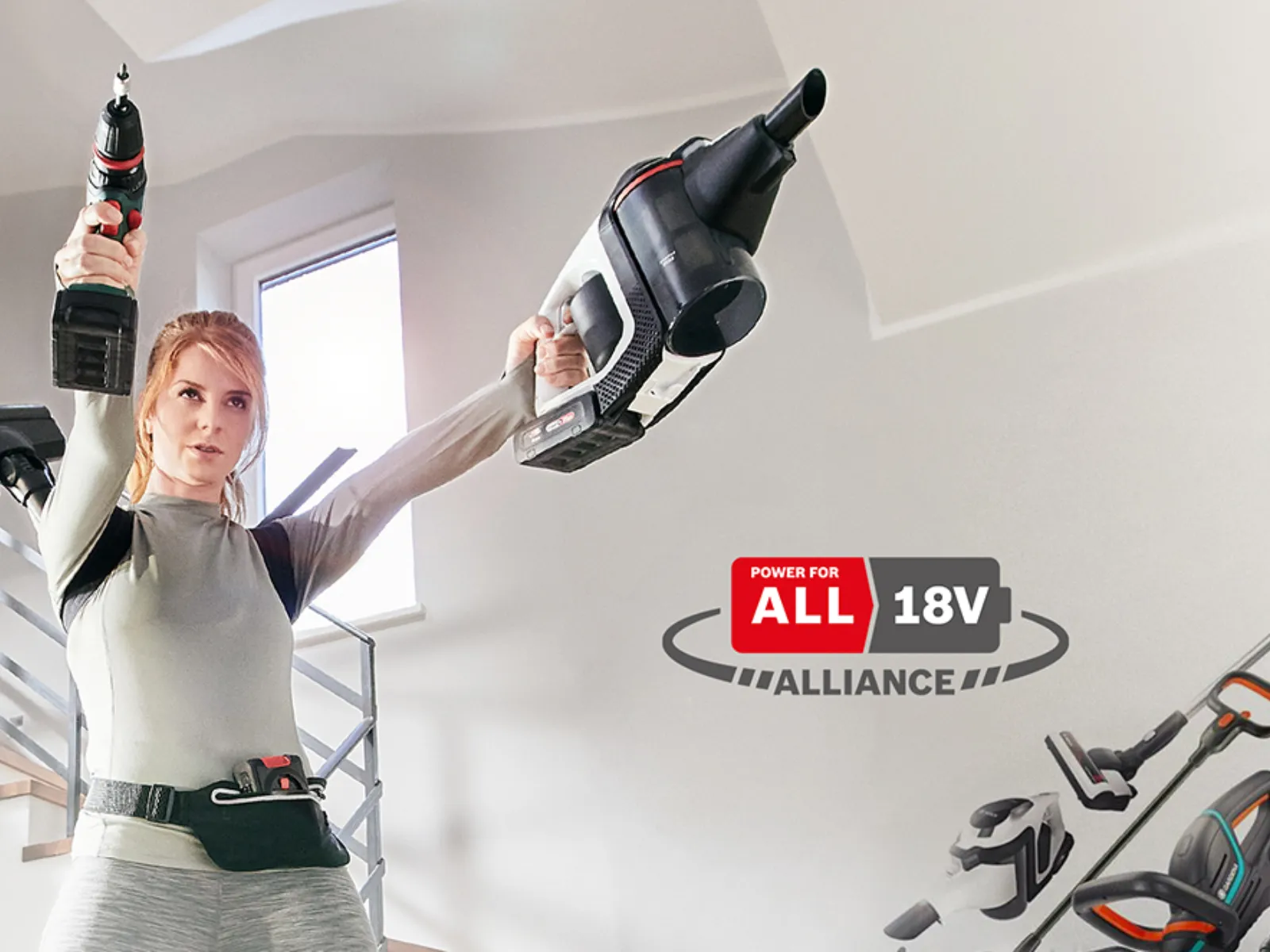 En kvinna håller en borr och handdelen av en skaftdammsugare som ett par pistoler. 18V Power for All Alliance-logotypen och en flod av verktyg och apparater leder till 18V-laddaren bredvid henne.