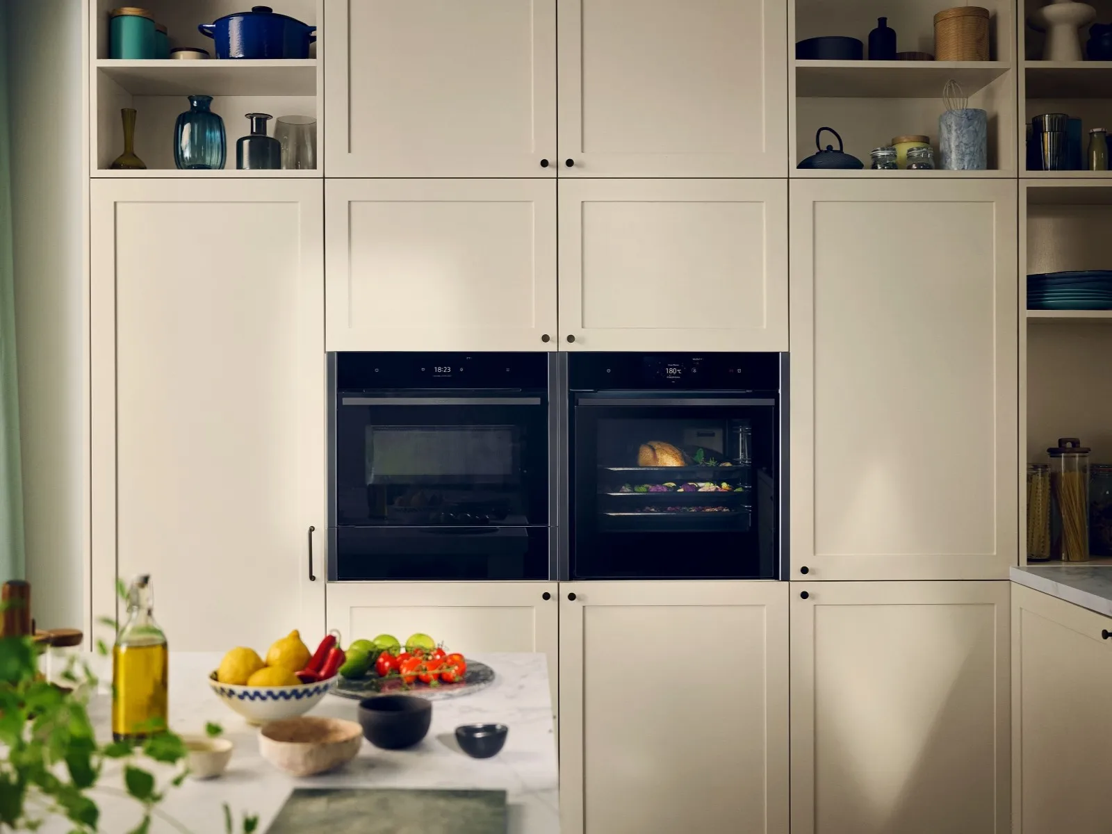 Light kitchen with colourful food on countertop and two NEFF built in cooking appliances in cabinet