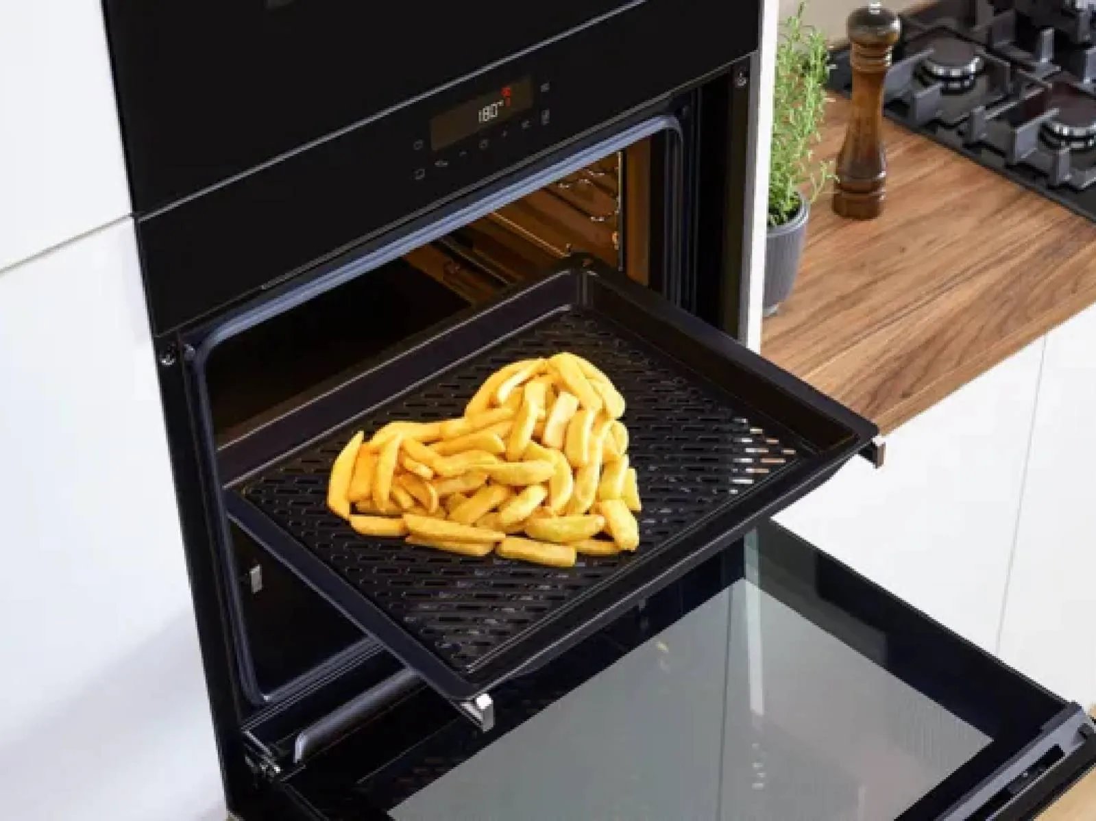 A Bosch oven bakes golden fries in a modern kitchen, complete with a stylish wooden countertop and gas stove.