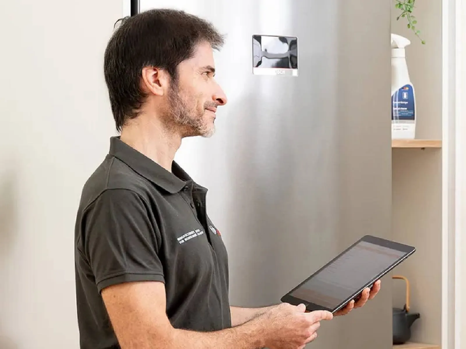 Cliente e técnico com um iPad a conversar numa cozinha em frente ao frigorífico.