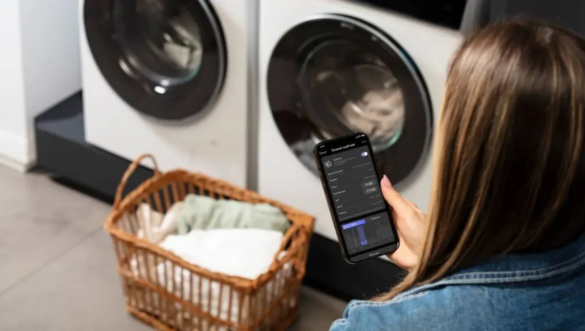 Femme consultant son smartphone près d'une machine à laver Siemens, avec un panier de linge propre.
