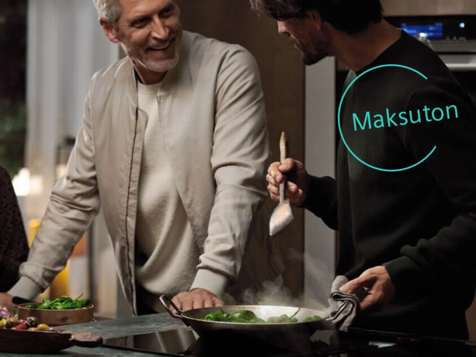 Joukko ihmisiä keskustelee keittiössä ja valmistaa ruokaa. Vieressä teksti: "Maksuton".