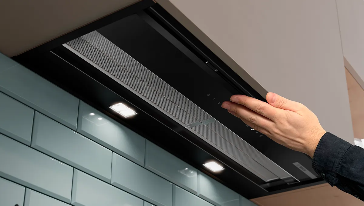 Mano che attiva una cappa da cucina nera elegante e moderna con illuminazione a LED integrata.