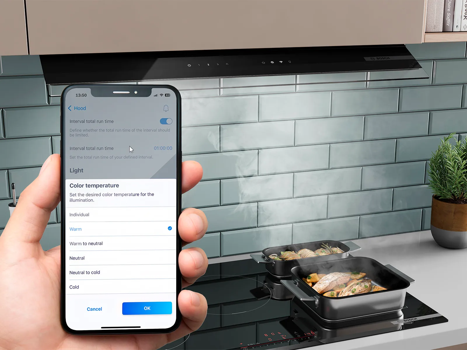 Jemand bedient eine Bosch Dunstabzugshaube über einem Kochfeld mit dampfendem Essen per Smartphone-App.