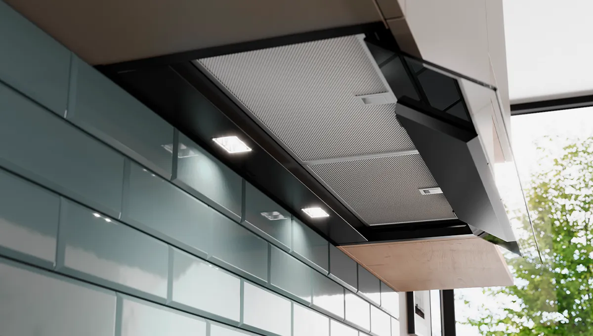 Moderna cappa da cucina con luci a LED integrate e filtri a rete, sopra una parete piastrellata.