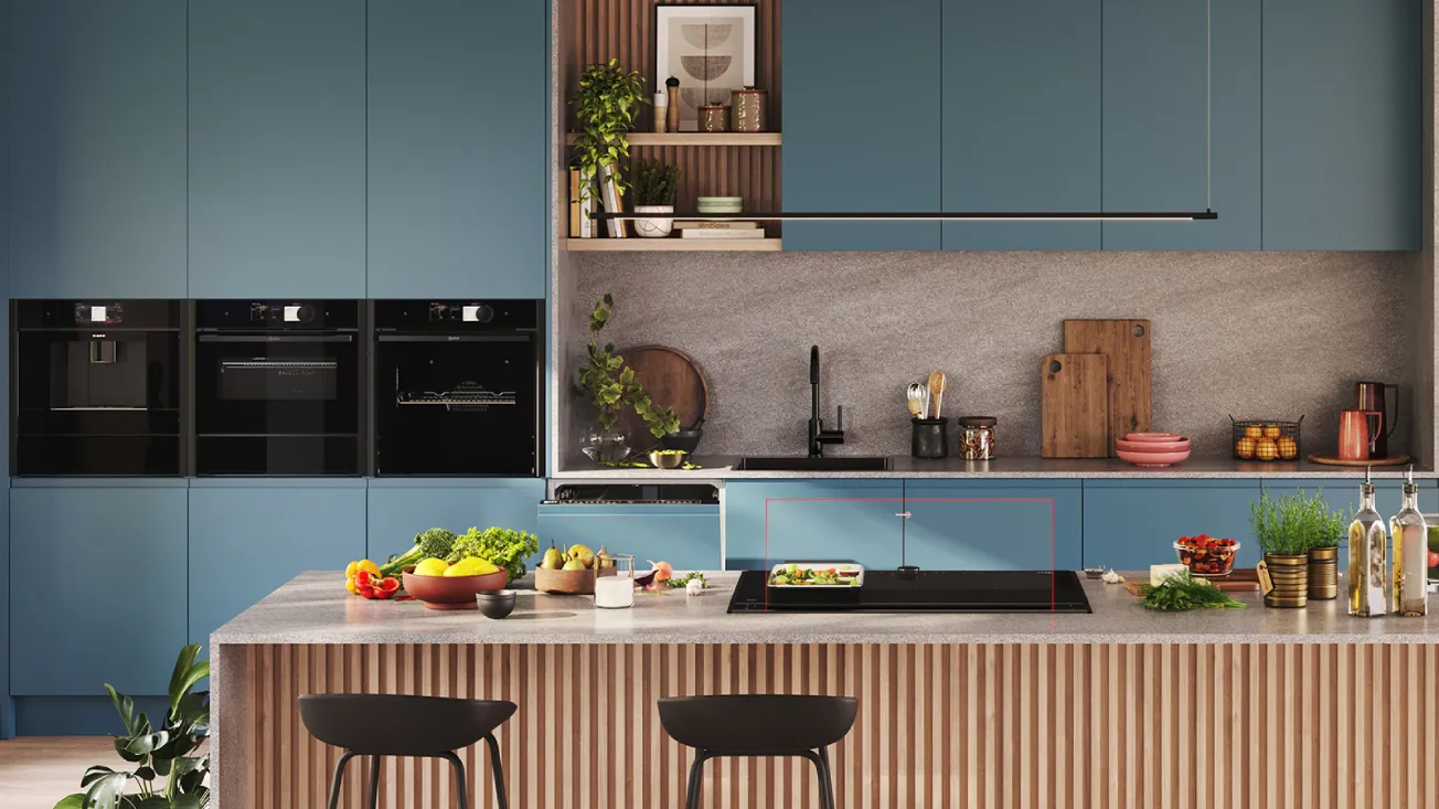 Contemporary kitchen with blue cabinets and three black built‑in ovens; gray stone countertop with black sink and faucet, open shelves with plants and cutting boards; wood‑slatted island topped with fruit bowls, an glass draft cooktop and two black bar stools.