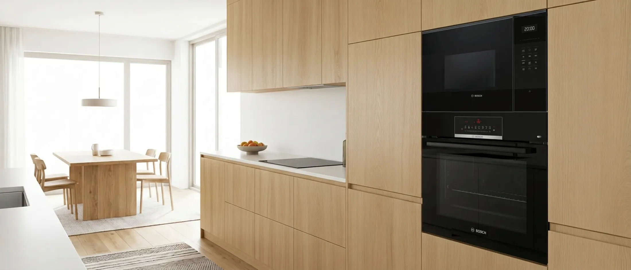 Built-in Bosch microwave seamlessly integrated on top of an oven into a modern white and wood kitchen design.
