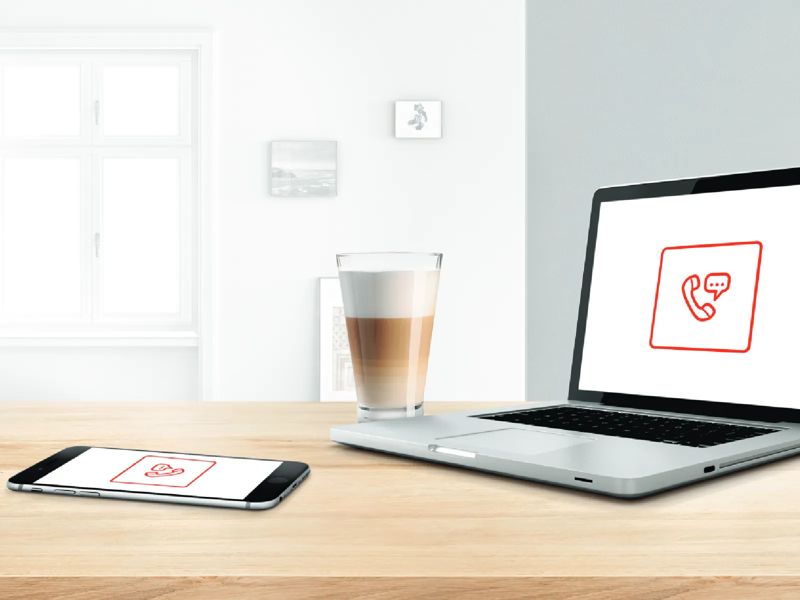 Laptop og smartphone viser ikoner for samtaler på et træbord med en kop kaffe.