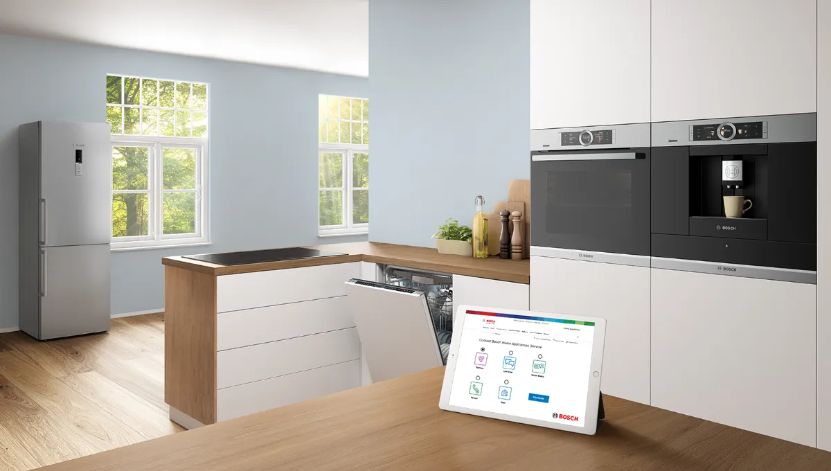 Tablette montrant la page de contact de Bosch sur un comptoir en bois dans une cuisine blanche.