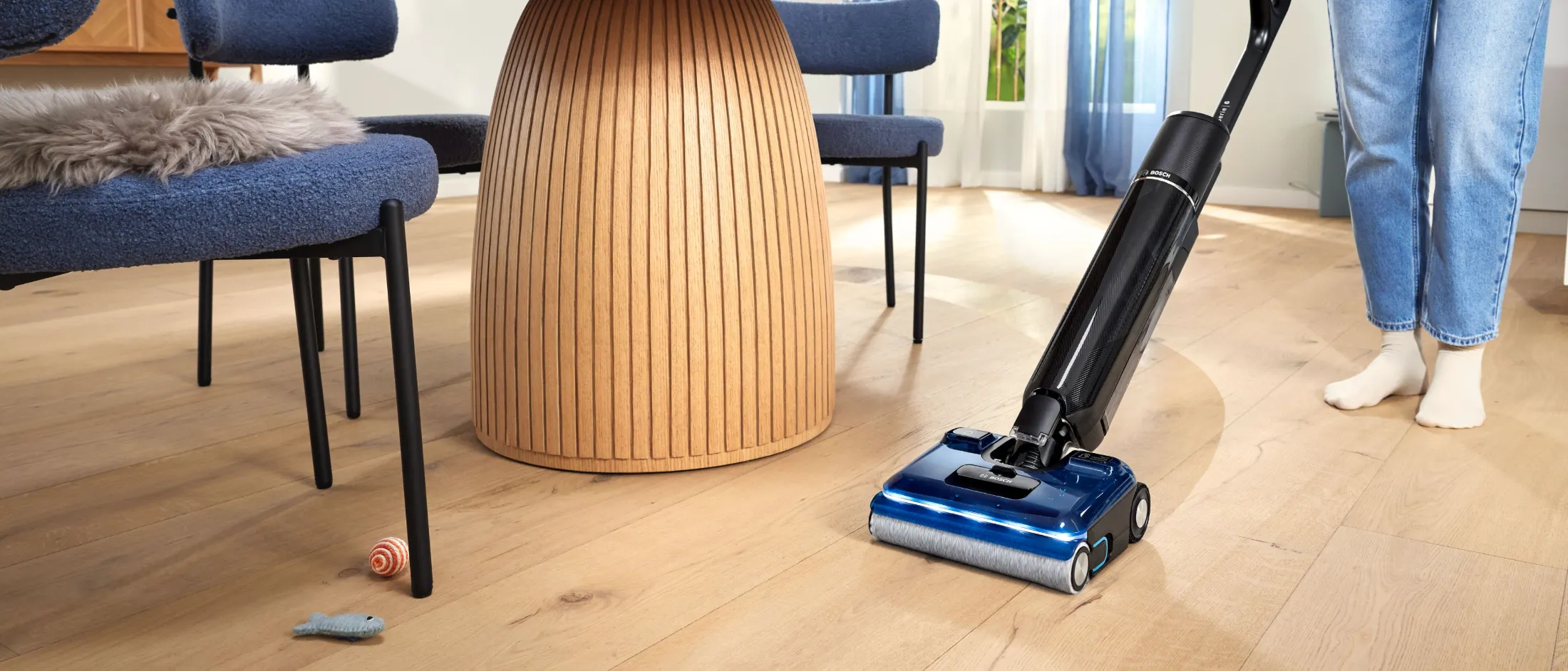  Una ragazza che pulisce un pavimento in legno chiaro con la lavapavimenti Serie 6