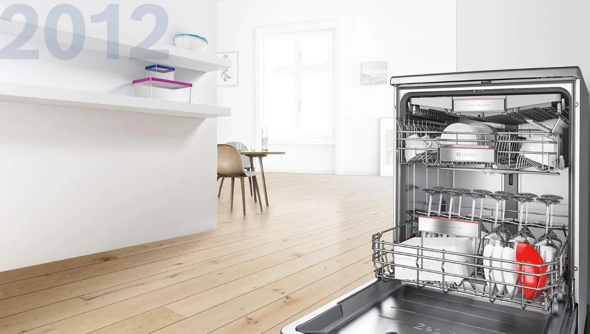 Open Bosch dishwasher fully loaded with dishes, glasses and cutlery in a bright modern kitchen, 2012.