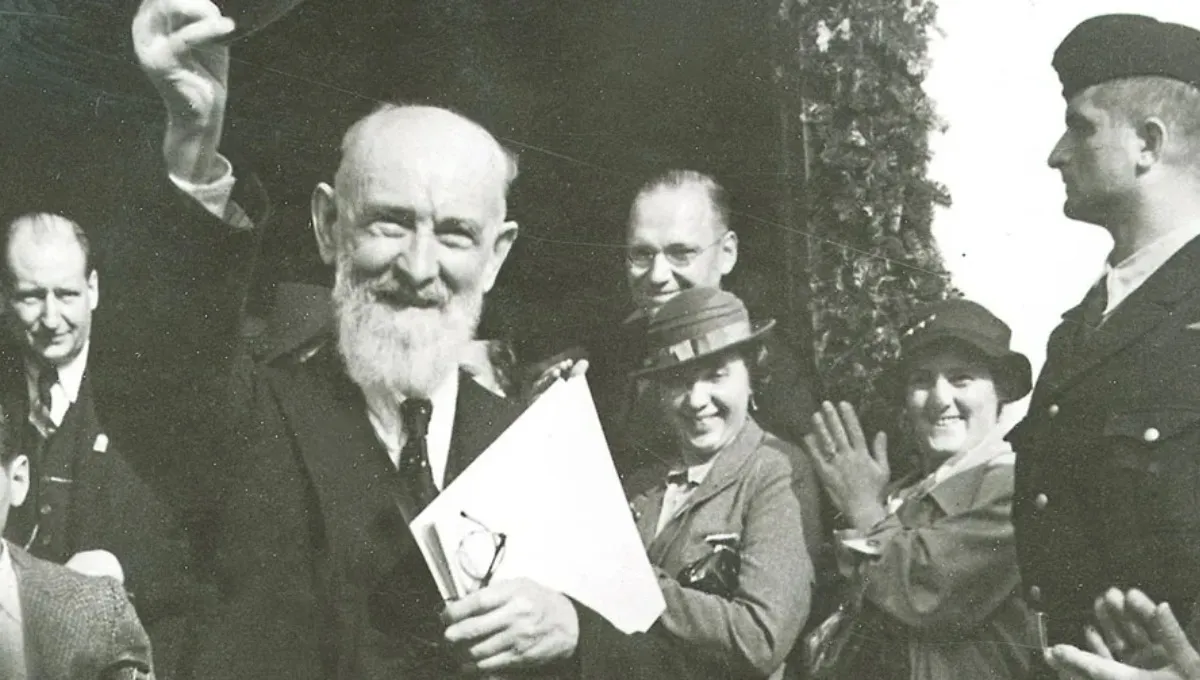 Vintage black-and-white photo of Robert Bosch waving to a crowd of smiling employees.