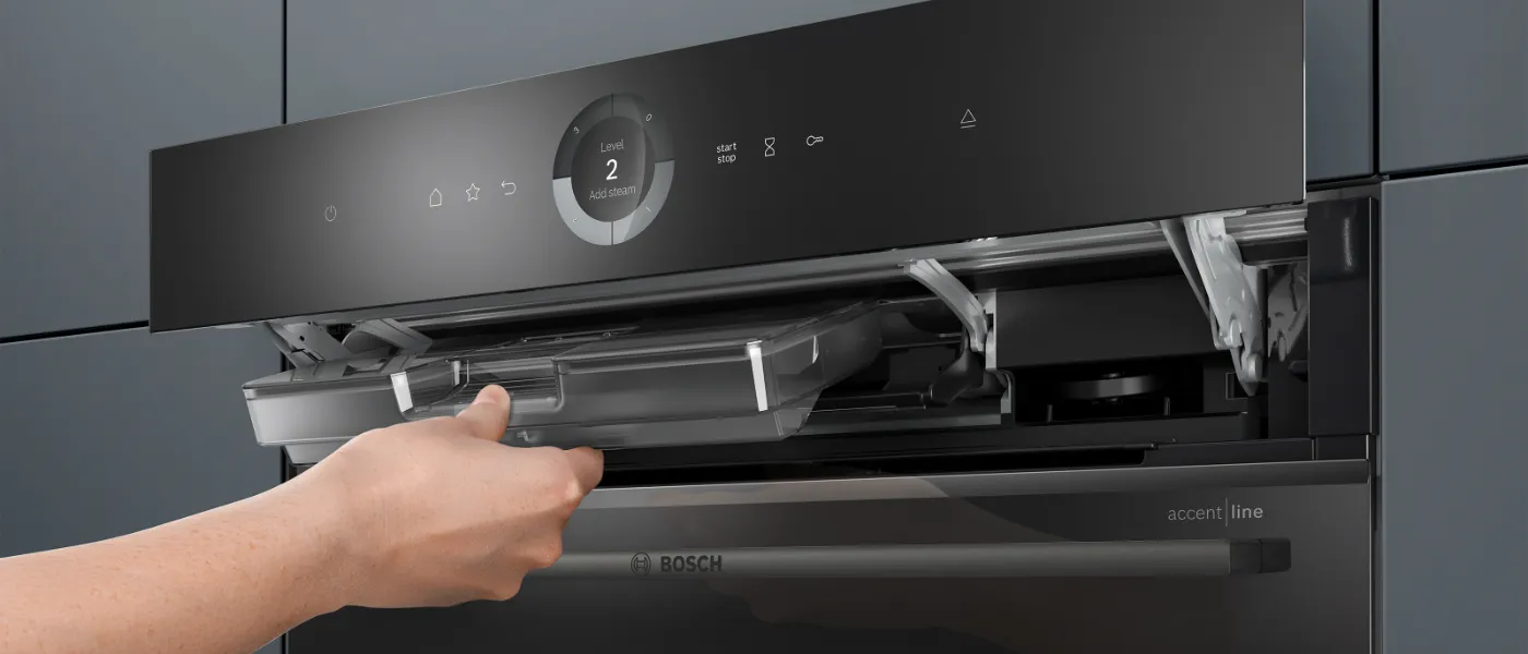Series 8 accent line oven. A person pulls out the water tank, which is located behind the flipped-open display.