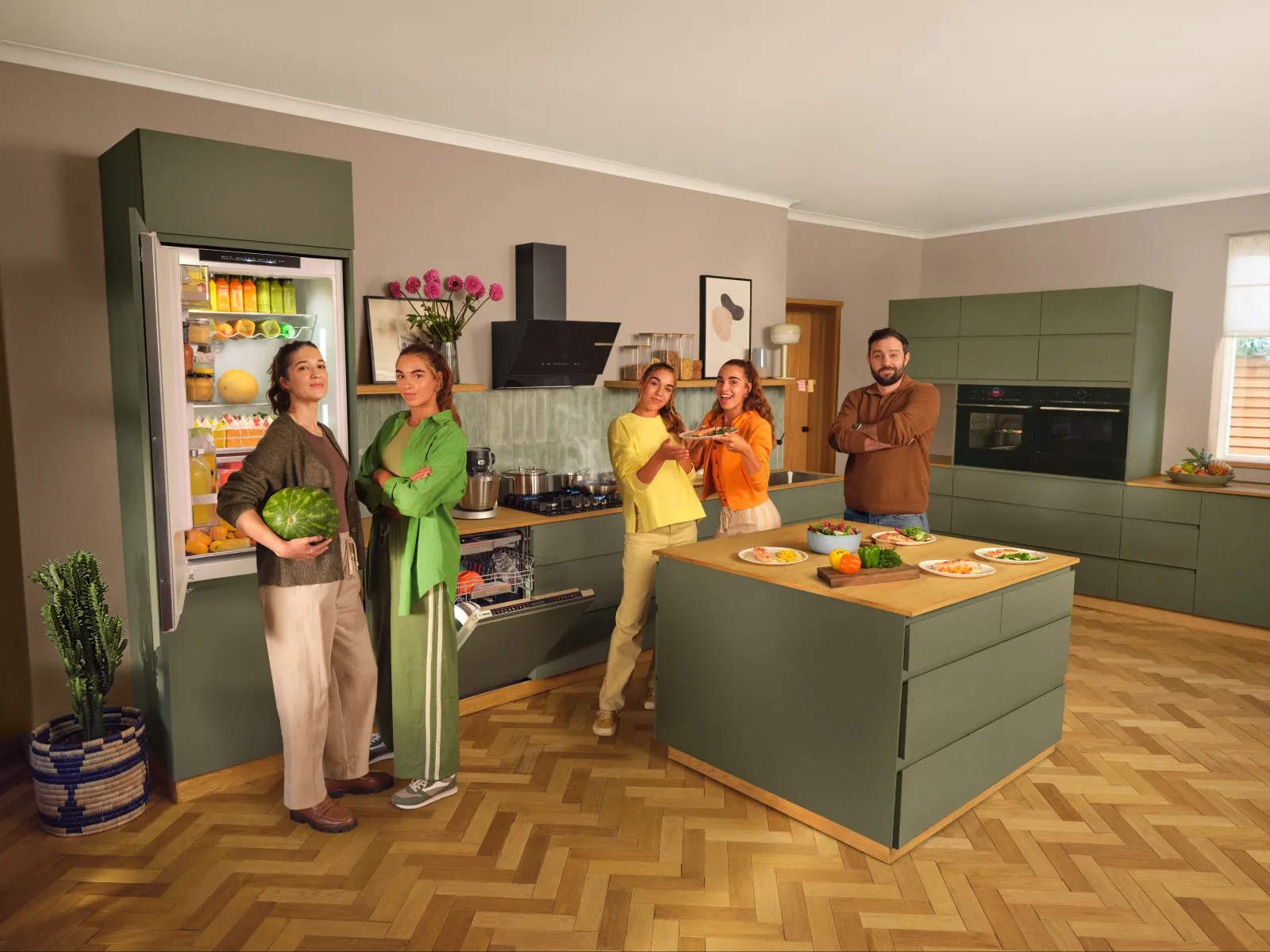 Family with teenage kids cooking and sharing a meal in a modern green Bosch kitchen.
