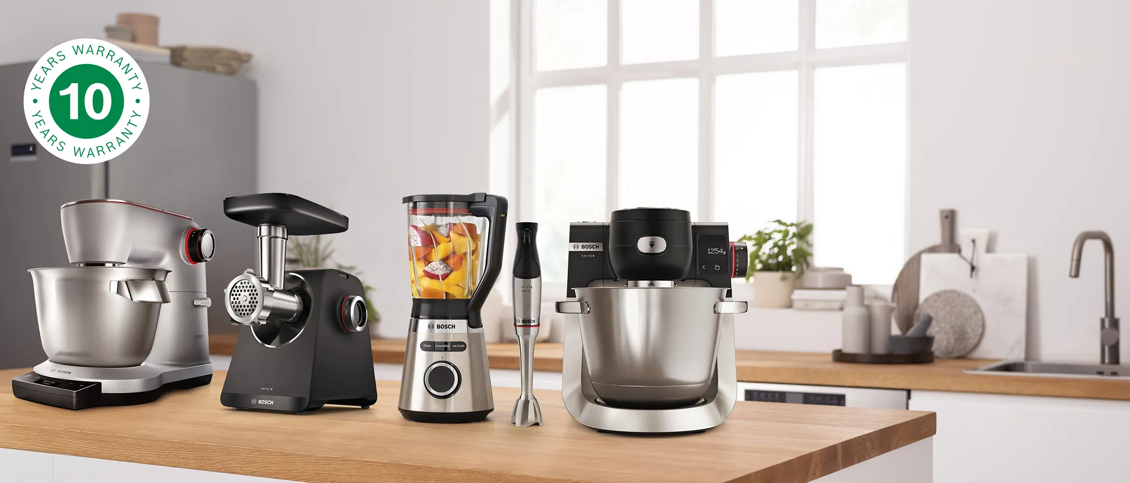 Robô de cozinha Serie 8, Liquidificador VitaPower Série 4 e varinha ErgoMaster Série 6 de pé sobre uma bancada, ao lado do logo de 10 anos de garantia.