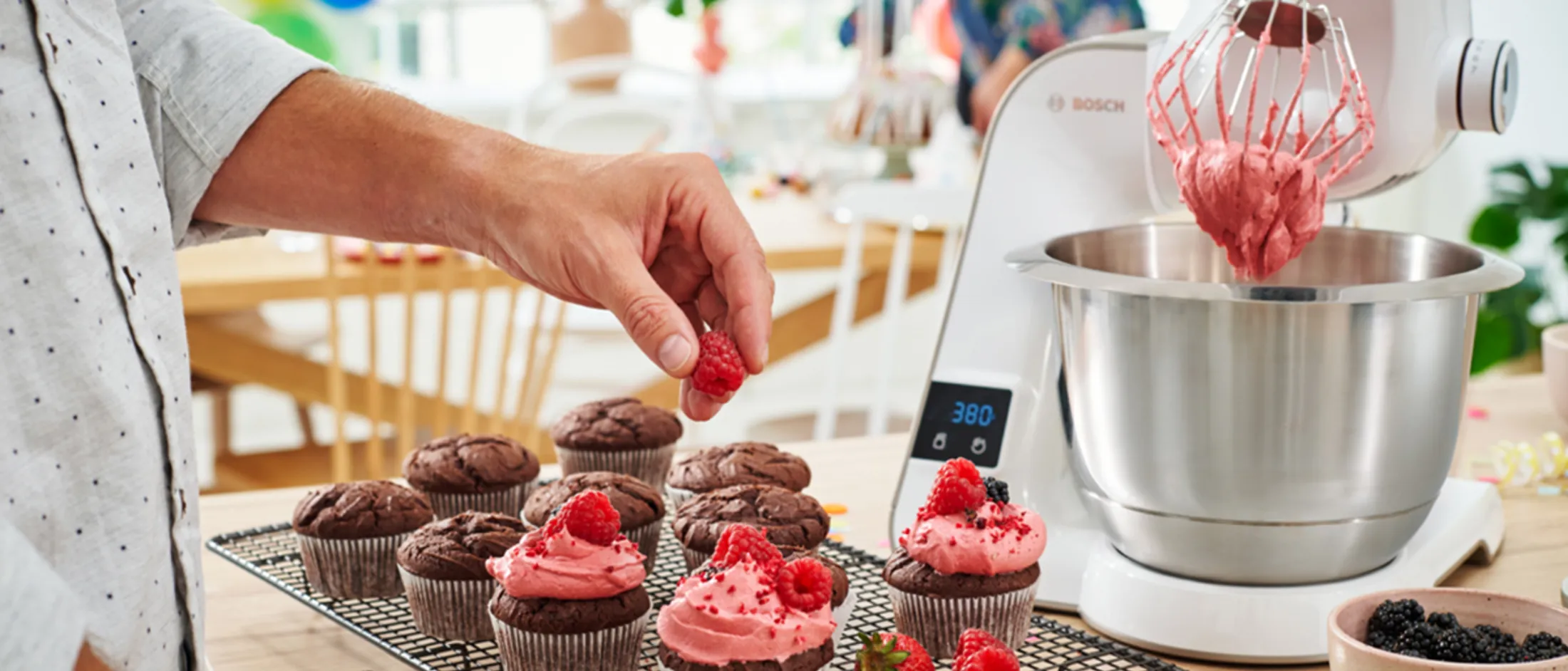 Homemade cupcakes, strawberries, and a cup of coffee on a rustic wooden table.