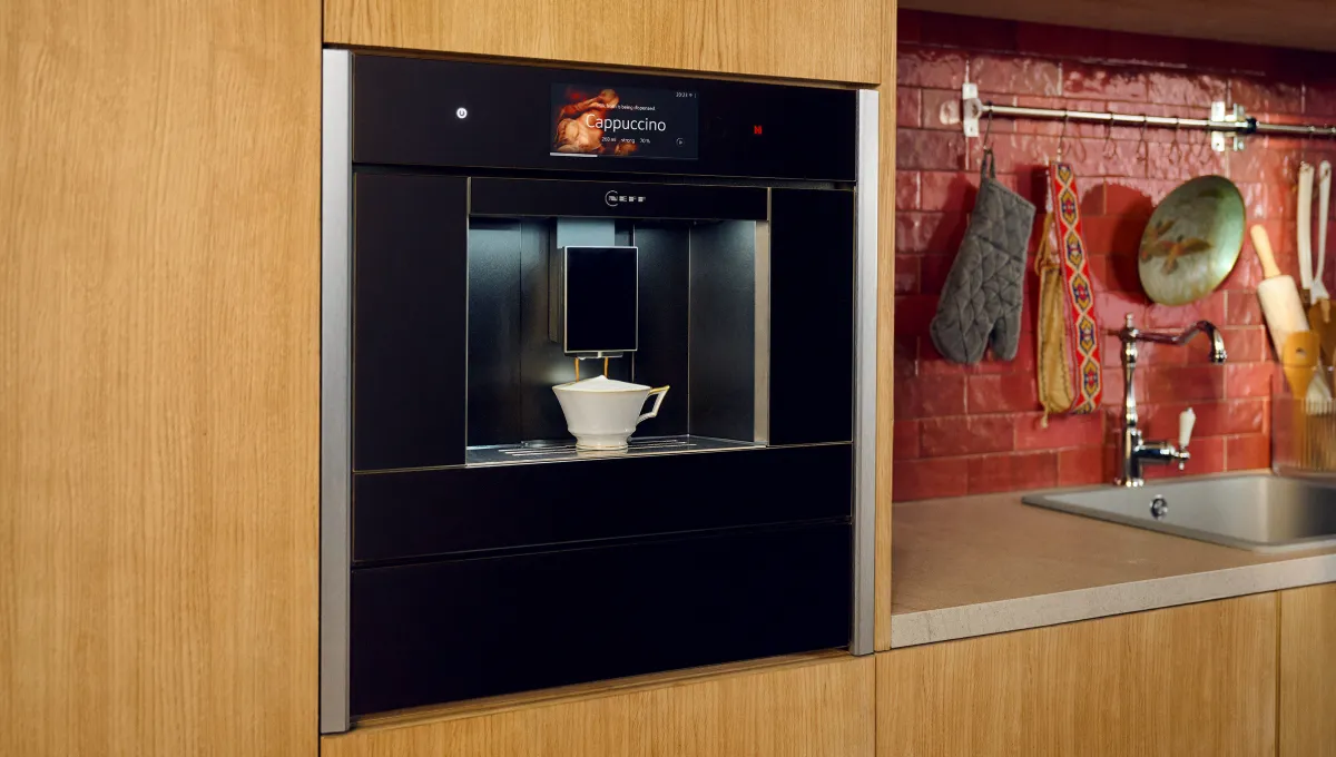 Built-in coffee machine, wooden cabinets, brick backsplash, kitchen sink, cooking utensils.
