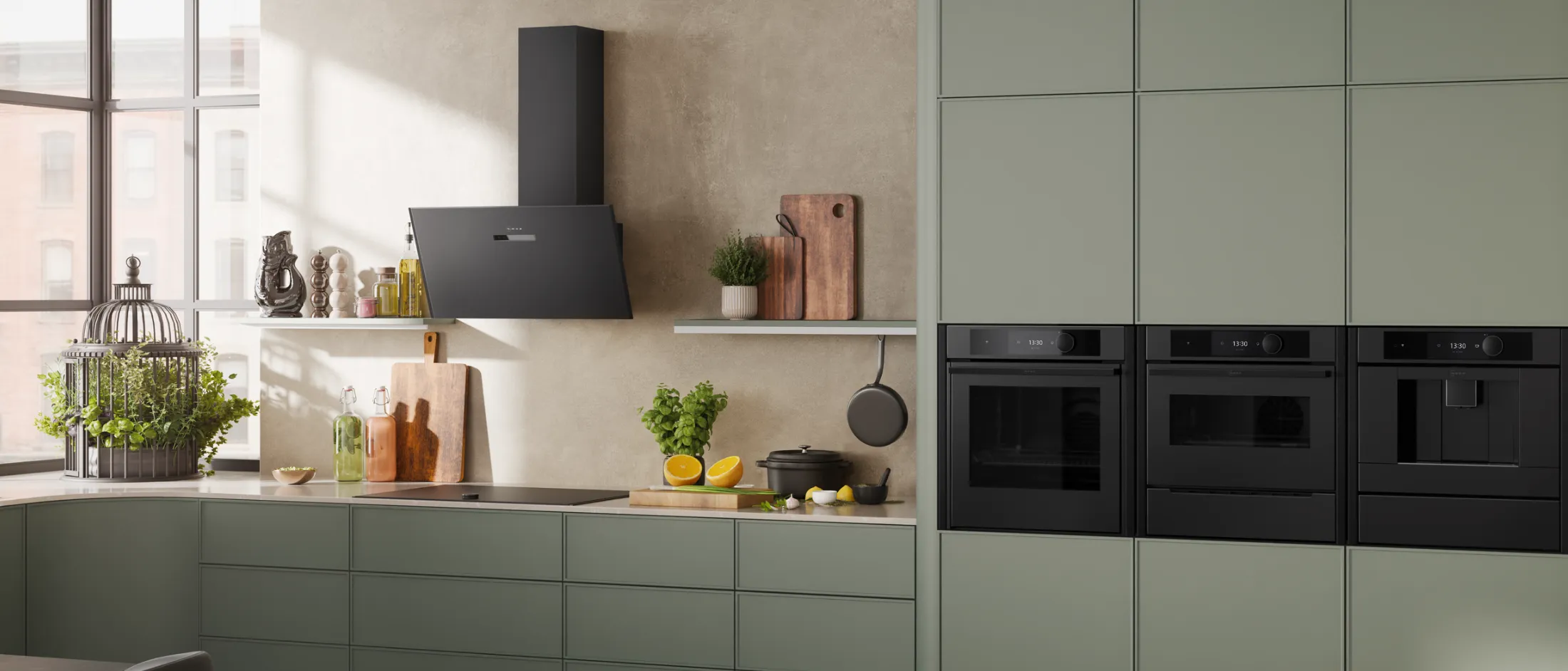 Bright, modern kitchen with sage green cabinets, black appliances, wood floor, dining table, and large windows.