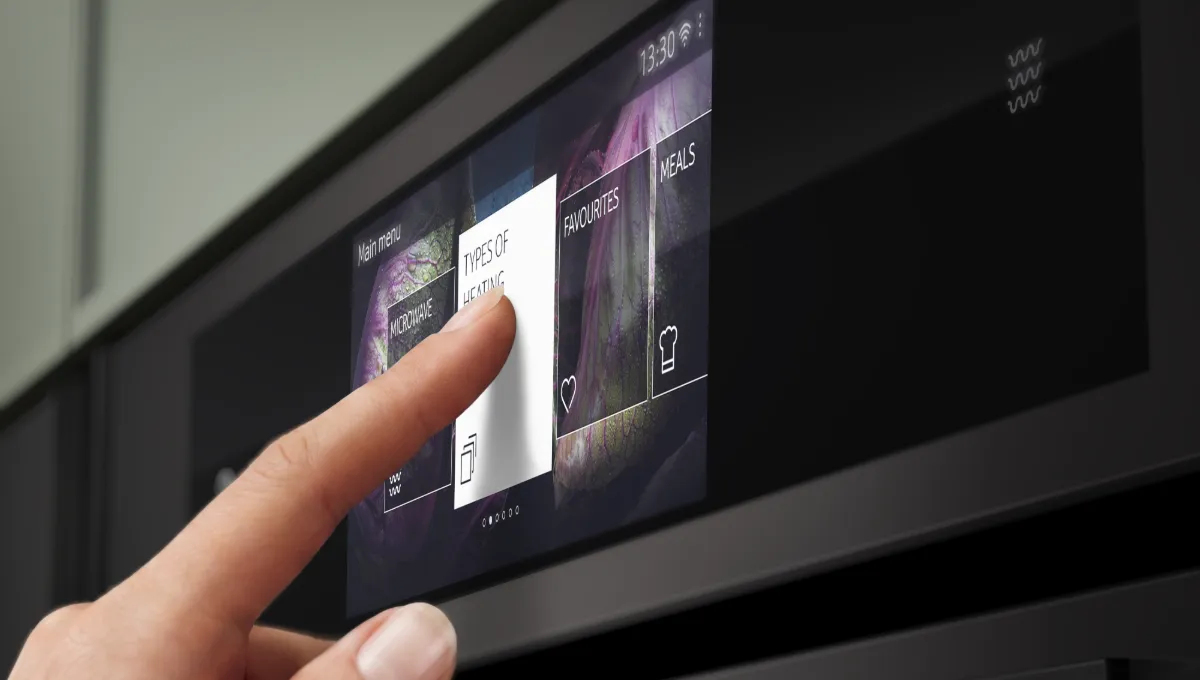 A hand interacts with a smart oven's touchscreen, selecting "Types of Heating" from the menu.
