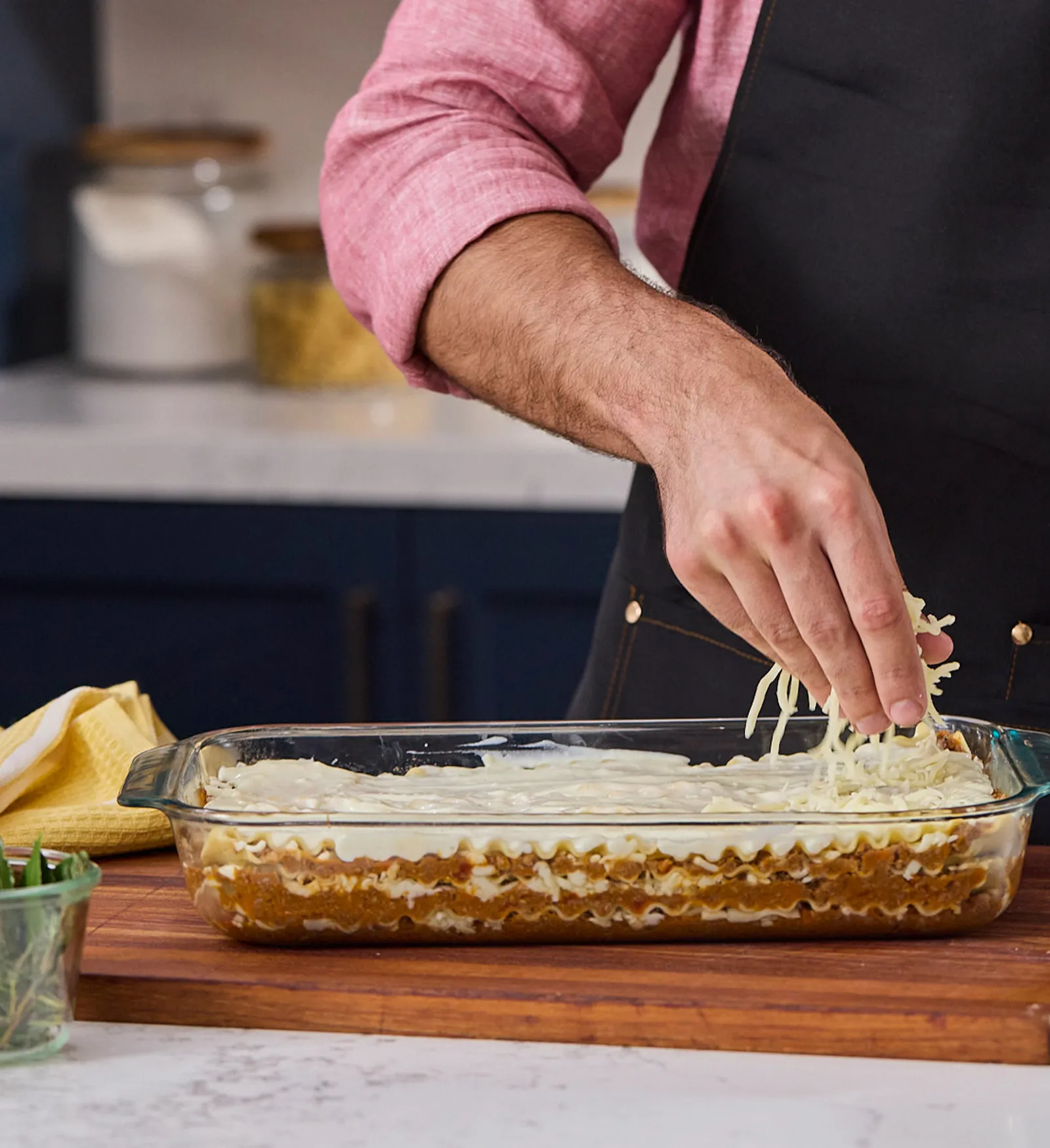 Chef layering lasagna sheets over the Bolognese and béchamel sauce